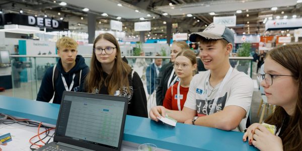 Kinder stehen an einem Messestand und sind aufmerksam